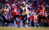 Jeff McIntosh
/ The Canadian Press
Winnipeg Blue Bombers' Darvin Adams, centre, runs the ball in for a touchdown as Calgary Stampeders' Joe Burnett, (24) and Jamar Wall (29) look on during second half CFL football action in Calgary, Saturday, July 18, 2015.