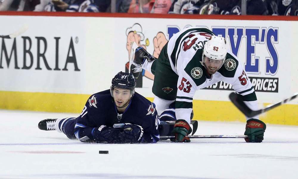 Trevor Hagan / The Canadian Press
Winnipeg Jets forward Alexander Burmistrov and Minnesota Wild counterpart Alex Tuch keep an eye on the puck after colliding during second-period pre-season NHL action Thursday in Winnipeg.