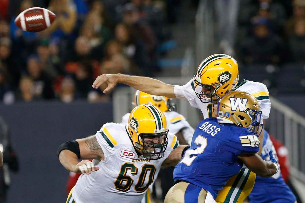 John Woods / The Canadian Press
Edmonton Eskimos quarterback Mike Reilly gets the pass away despite getting hit by Winnipeg Blue Bombers' Khalil Bass during the second half of CFL action in Winnipeg Friday.
