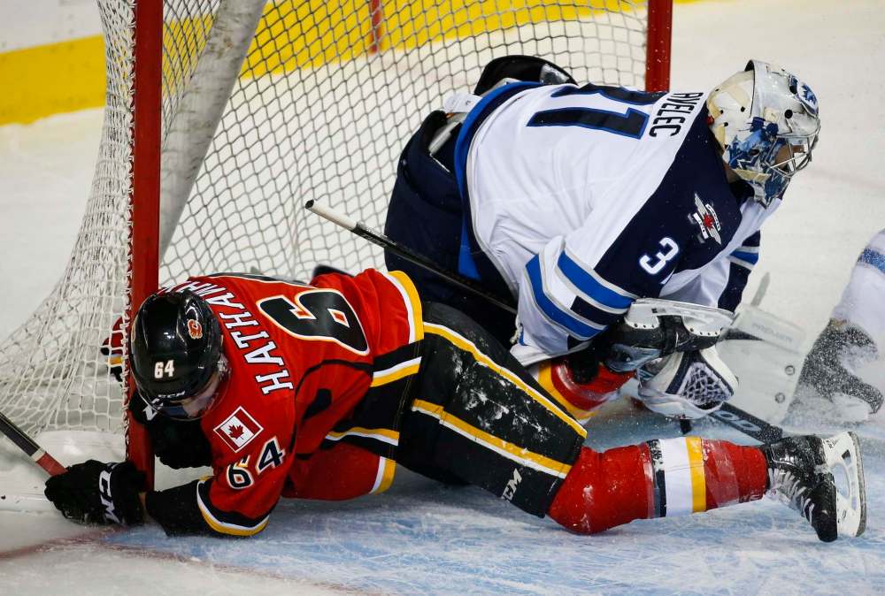 JEFF MCINTOSH / THE CANADIAN PRESS
Winnipeg Jets' goalie Ondrej Pavelec (right) is taken down by Calgary Flames' Garnet Hathaway during first period pre-season NHL hockey action in Calgary Sunday.