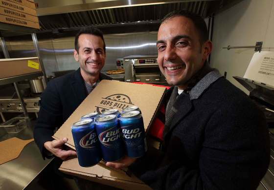 PHIL HOSSACK / WINNIPEG FREE PRESSAnthony Paletta (left) and his brother Angelo show off the merchandise inside the Ellice Avenue Holiday Inn. The Hops Pizza co-owners are the first in Canada to deliver pies and beer.