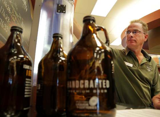 COLIN CORNEAU / BRANDON SUN FILESJeff Wolfe, assistant manager at the 10th and Victoria Liquor Mart in Brandon, pours the first fill of a growler in 2014.