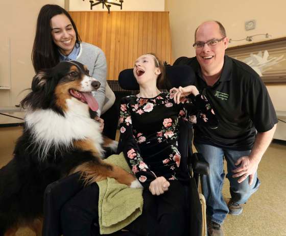 JASON HALSTEAD / WINNIPEG FREE PRESSLawyer Joelle Pastora Sala, left, Amy Hampton and David Kron of the Cerebral Palsy Association of Manitoba with Hampton’s dog Chase at Ten Ten Sinclair Housing Inc. Before she became an adult, Hampton received one-on-one support, occupational therapy, physiotherapy, speech therapy, orthotics, care at a spasticity clinic, medical supplies and equipment. That ended when she turned 18