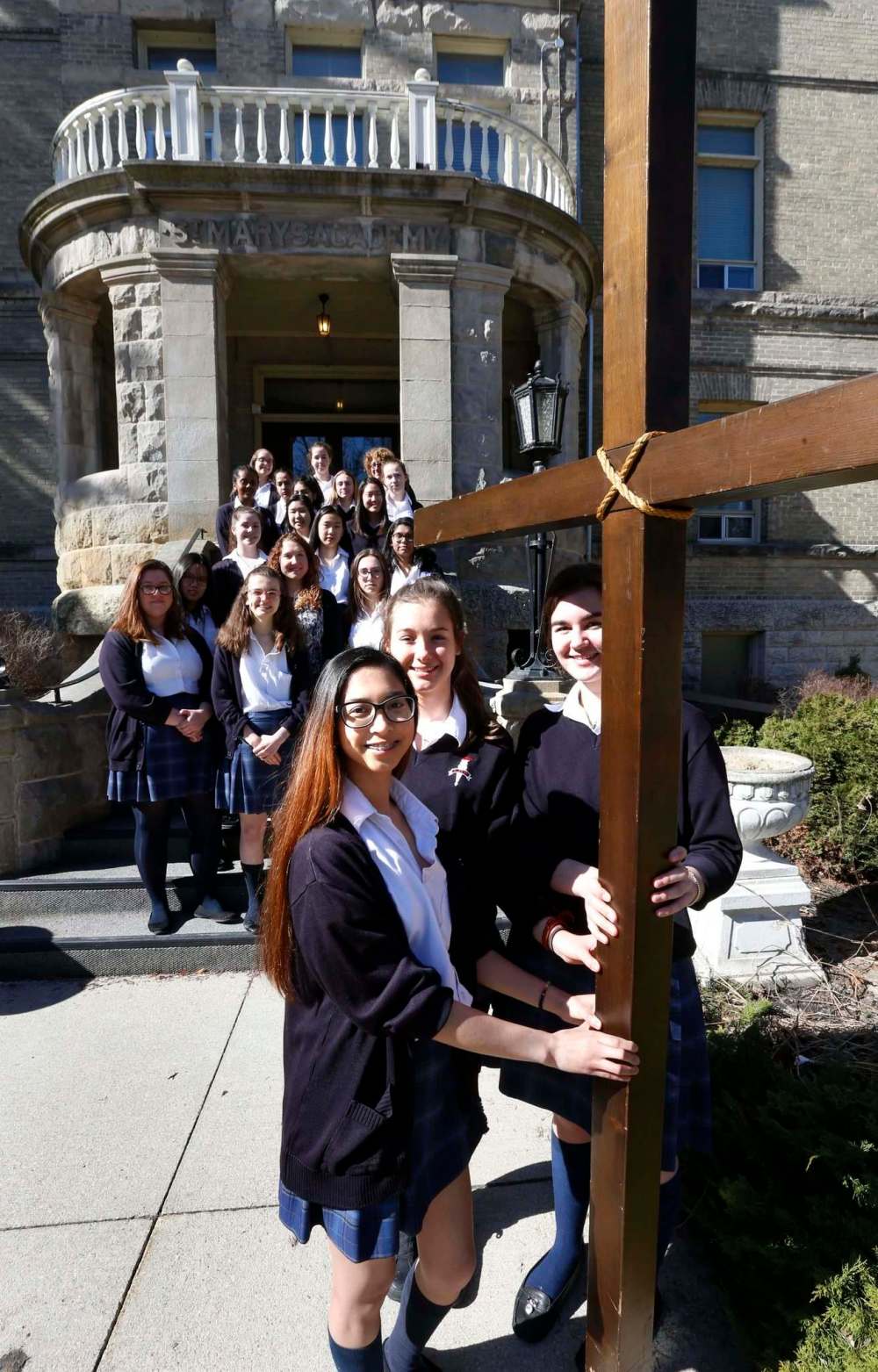 Students (left to right) Alliah Ramirez, Deirdre Beaumont and Marysa Fosty hold the cross to be used on Good Friday in front of St. Mary's Academy. (Wayne Glowacki / Winnipeg Free Press)