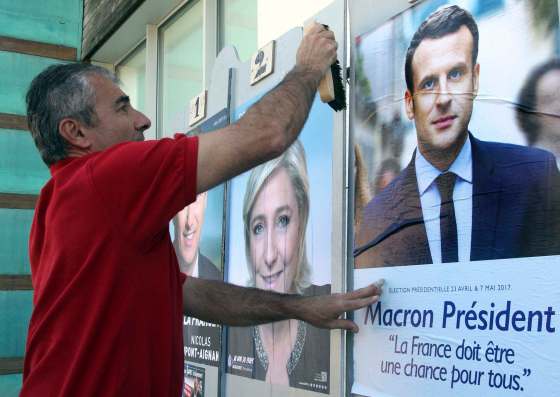 BOB EDME / THE ASSOCIATED PRESSChristophe Sanz, a supporter of French centrist presidential candidate Emmanuel Macron, glues a campaign poster next to one of far-right candidate Marine Le Pen.