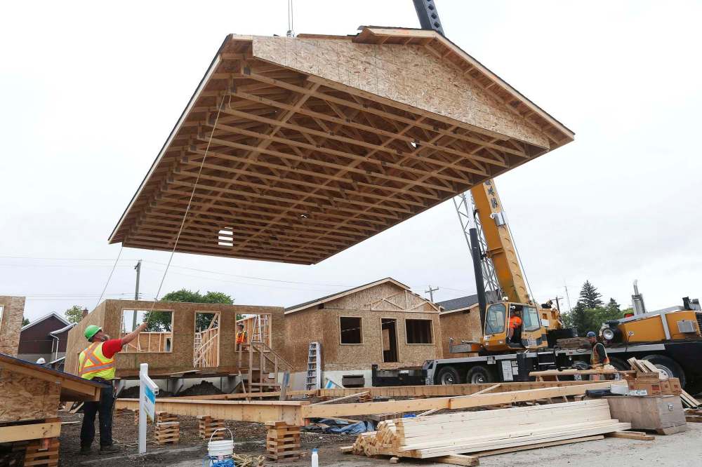 JOHN WOODS / WINNIPEG FREE PRESS
Construction crews raise the roofs on twenty homes at the Habitat For Humanity build on Lyle Street, Tuesday.