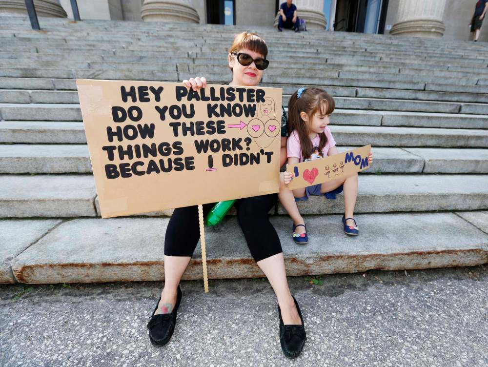 JUSTIN SAMANSKI-LANGILLE / WINNIPEG FREE PRESS
Julie Mungall and her daughter Islay hold up signs in front of the legislature building protesting Manitoba Government cuts to the Health Sciences Centre's Women's Hospital Lactation Consultant program.