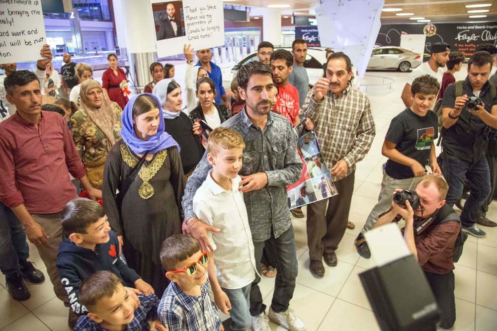 JUSTIN SAMANSKI-LANGILLE / WINNIPEG FREE PRESS
Emad Mishko Tamo, 12, centre, his mother Nofa Mihlo Rafo, left, and uncle Hadji Tamo move through a large crowd of supporters and media at Winnipeg's James Armstrong Richardson International Airport early Thursday morning after being re-united.