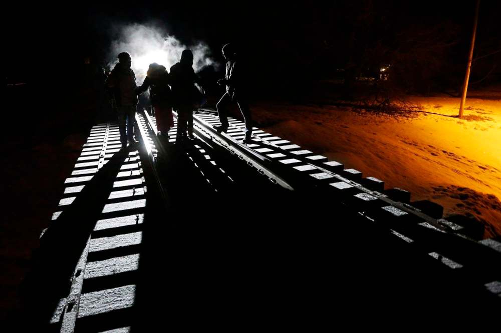 JOHN WOODS / THE CANADIAN PRESS FILES
Migrants cross into Canada from the United States by walking down a train track into the town of Emerson, Man., in February.