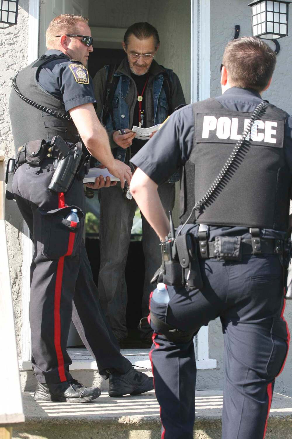 JOE BRYKSA / WINNIPEG FREE PRESS FILES
Police officers from the Winnipeg Police Service Community Support Division deliver leaflets door-to-door in Winnipeg's core to promote home crime prevention. Residents of Point Douglas fear the WPS redeployment of community support units to front-line duty may spell the end to these types of programs and have a negative affect on their community.