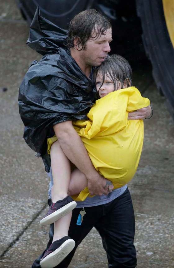 David J. Phillip / The Associated PressA man carries a girl in Houston.