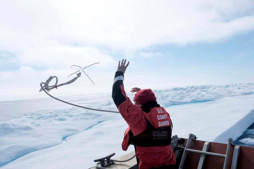 Coast Guard Petty Officer 3rd Class Brandon Arciello, a boatswain’s mate, slings an anchor to tether a small boat during dive exercises in the Arctic Ocean.