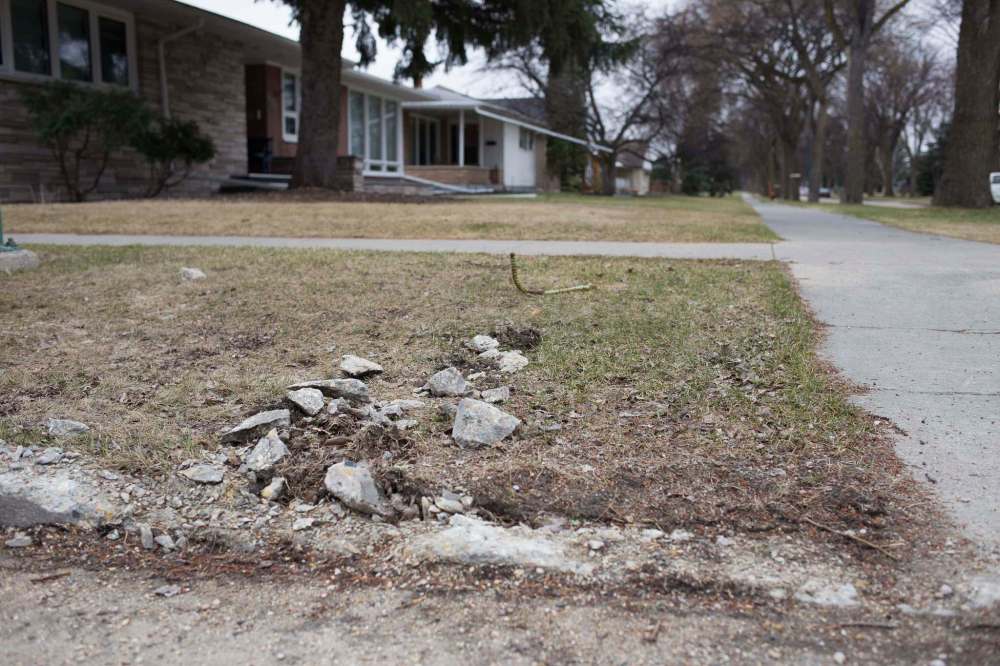The rubble of a curb lies across the boulevard of Fleet Avenue at Queenston Street in April. Private contractors are responsible for repairing damage their crews cause, but taxpayers have to pick up the cost for civic crews. (Jen Doerksen / Winnipeg Free Press files)
