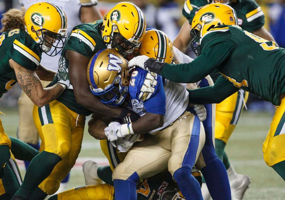 JASON FRANSON / THE CANADIAN PRESS
Winnipeg Blue Bombers' Timothy Flanders (20) is tackled by the Edmonton Eskimos during second half CFL action in Edmonton, Alta., on Saturday September 30, 2017.