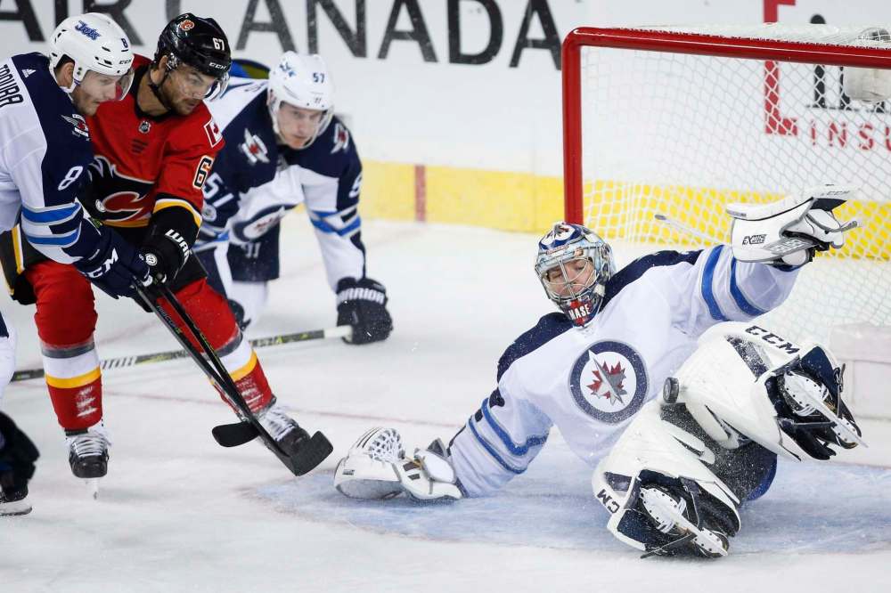 JEFF MCINTOSH / THE CANADIAN PRESS
Winnipeg Jets goalie Steve Mason, right, makes a save as Calgary Flames' Michael Frolik, second from left, from the Czech Republic, looks on during second period NHL hockey action in Calgary, Saturday, Oct. 7, 2017.