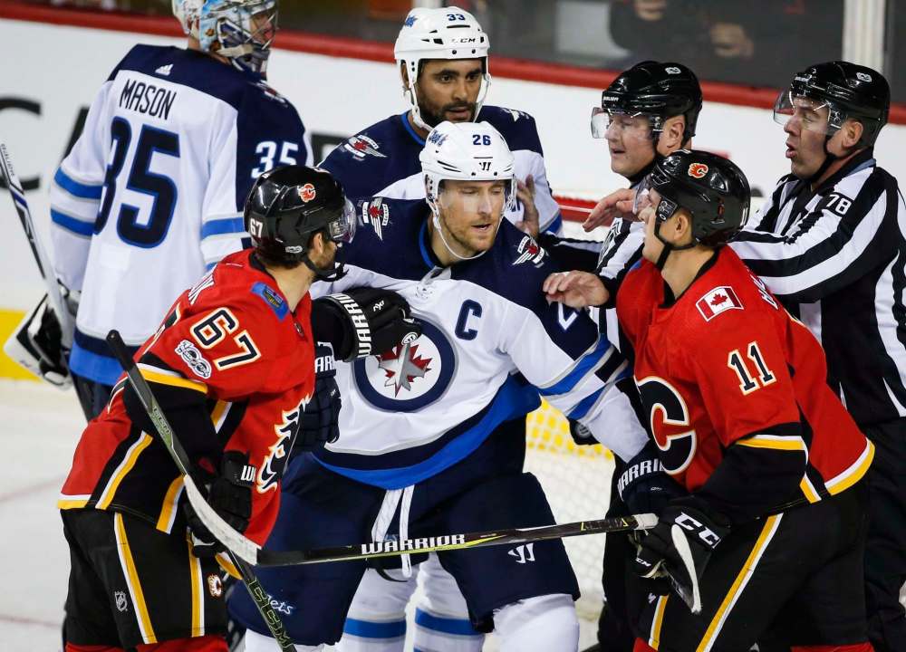 JEFF MCINTOSH / THE CANADIAN PRESS
Winnipeg Jets' Blake Wheeler, centre, tangle with Calgary Flames' Michael Frolik, left, from the Czech Republic, and Mikael Backlund, from Sweden, during second period NHL hockey action in Calgary, Saturday, Oct. 7, 2017.