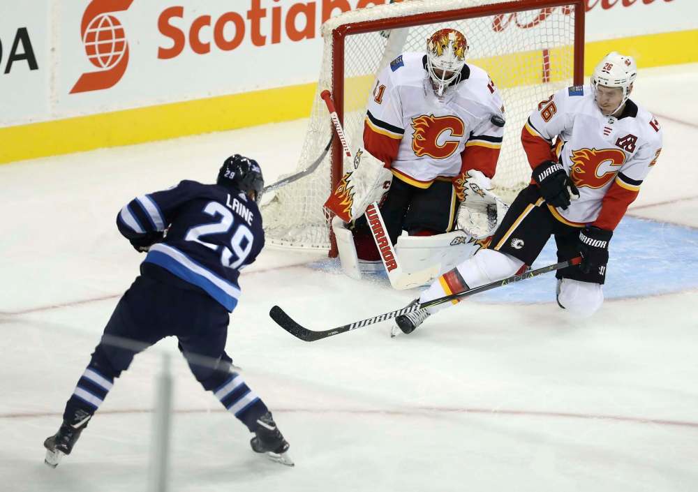 THE CANADIAN PRESS/Trevor Hagan
Winnipeg Jets' Patrik Laine fires a shot at Calgary Flames goaltender Eddie Lack with Michael Stone in front of the net.