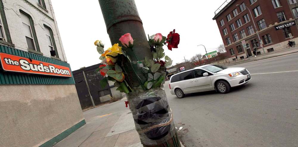 A memorial bouquet along with the victim's cap and a braid of sweetgrass mark the spot where Cody Severight was killed while walking in the area of Main Street and Sutherland Avenue. (Phil Hossack / Winnipeg Free Press files)