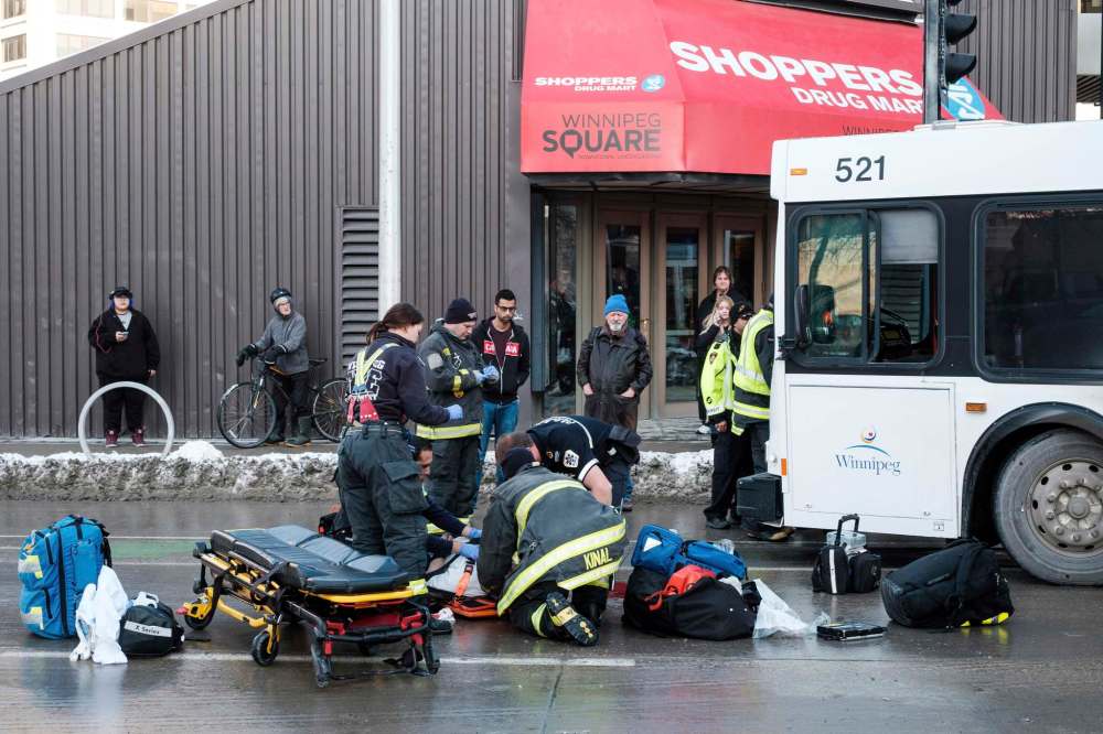 Daniel Crump / Winnipeg Free Press
First responders work on a man who was struck by a Winnipeg Transit bus at the corner of Graham Avenue and Fort Street Monday night.