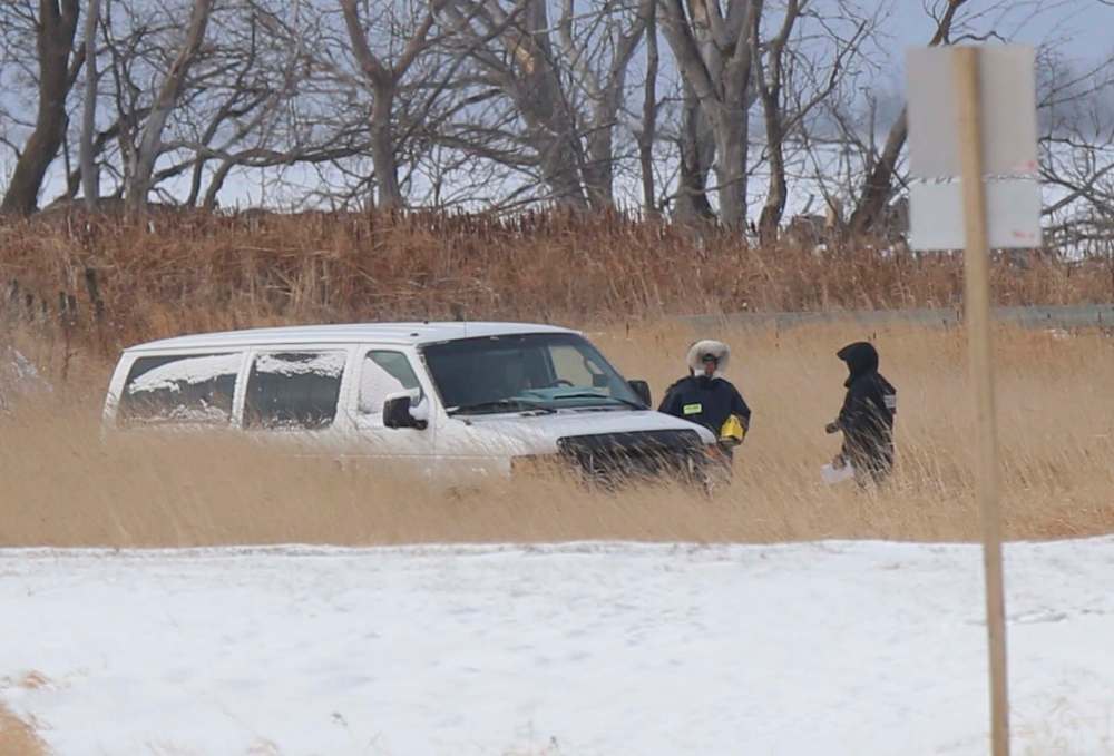 An unmarked white police van is seen at the bottom of a large snow-filled ditch off Highway 417 just south of the Lake Manitoba First Nation. (Wayne Glowacki / Winnipeg Free Press)