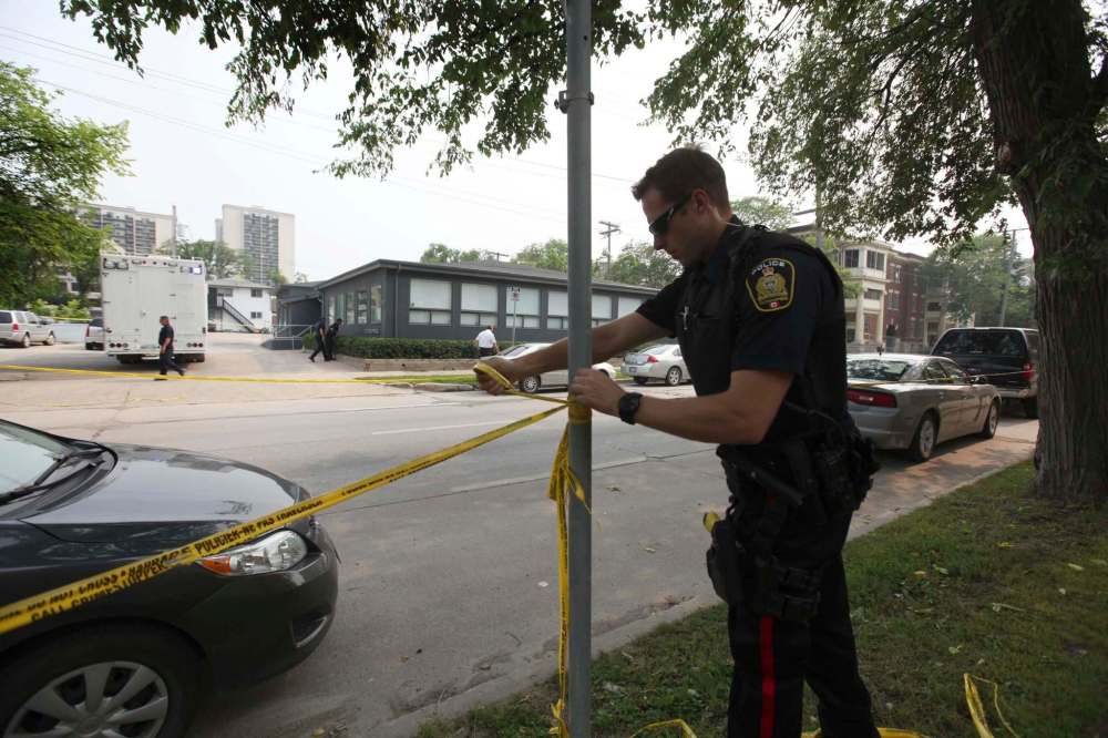 Ruth Bonneville / Winnipeg Free Press
A police officer keeps bystanders back from the Petersen and King Law Office at 252 River Ave. as officers officers take a close look at the window using a flashlight which appears to be broken and blood sprayed Friday afternoon in 2015.
