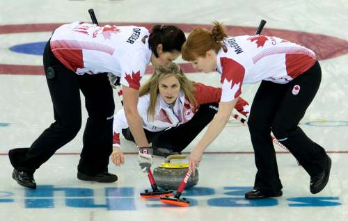Jones throws her last rock as Jill Officer and Dawn McEwen sweep during the Olympic curling final at the Sochi Winter Olympics in 2014. (Adrian Wyld / The Canadian Press files)