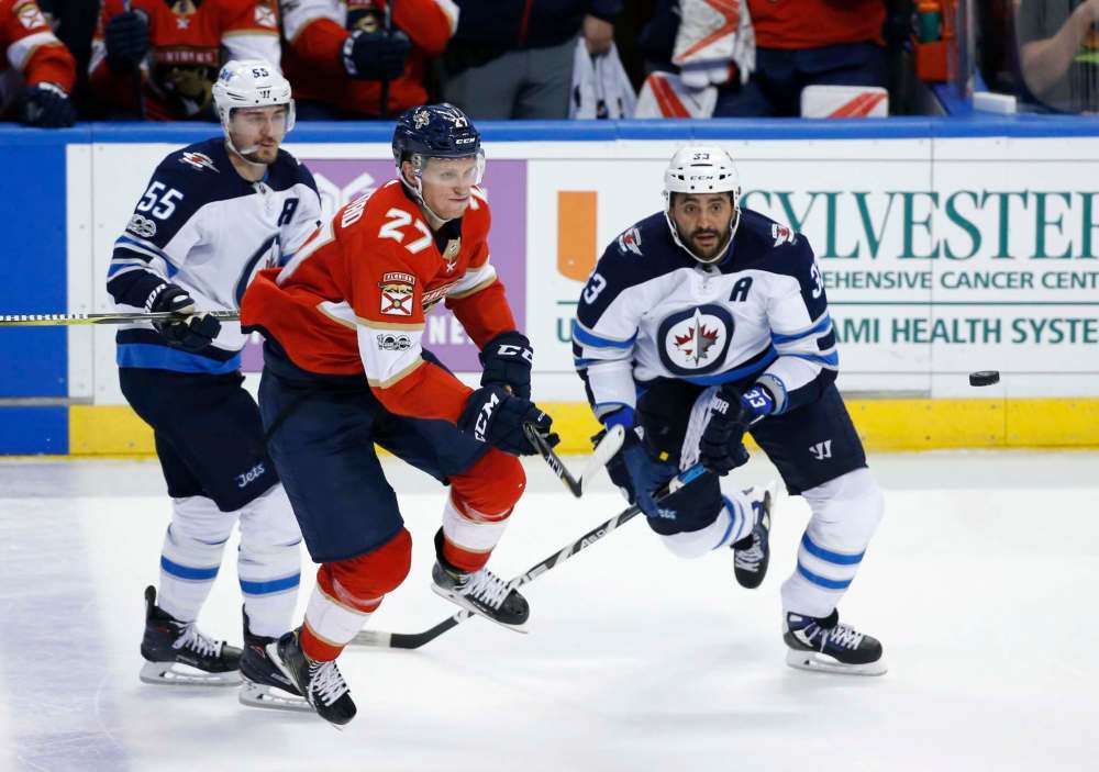 Winnipeg Jets defenseman Dustin Byfuglien (33) and center Mark Scheifele (55) compete for the puck with Florida Panthers center Nick Bjugstad (27) during the second period of an NHL hockey game Thursday, Dec. 7, 2017, in Sunrise, Fla. Byfuglien is expected to be out of the lineup until after Christmas with a lower-body injury suffered Saturday night in Tampa. (AP Photo/Wilfredo Lee)