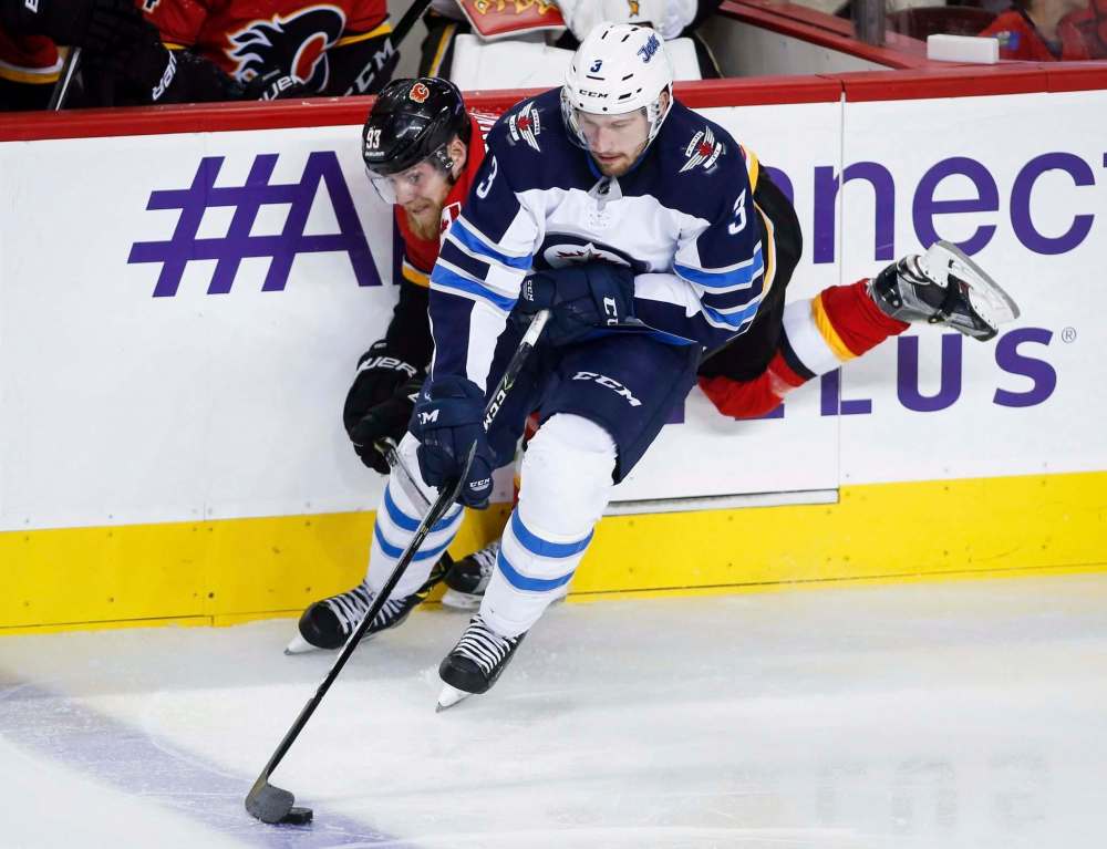 Jeff McIntosh / The Canadian Press files
Winnipeg Jets defenceman Tucker Poolman steals the puck from Calgary Flames forward Sam Bennett during a pre-season game. Poolman made the team out of training camp.