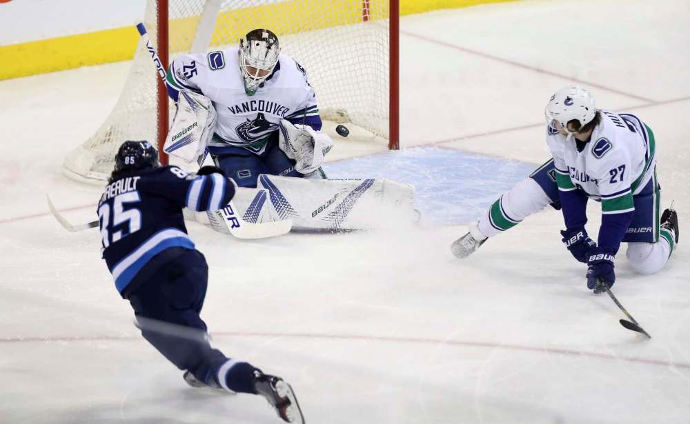 THE CANADIAN PRESS/Trevor Hagan
Vancouver Canucks goalie Jacob Markstrom stops a shot by Winnipeg Jets' Mathieu Perreault with Ben Hutton in front of the net during first period NHL hockey action in Winnipeg, Monday.