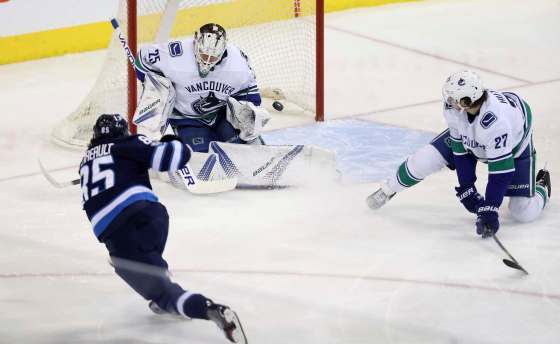THE CANADIAN PRESS/Trevor HaganVancouver Canucks goalie Jacob Markstrom stops a shot by Winnipeg Jets' Mathieu Perreault with Ben Hutton in front of the net during first period NHL hockey action in Winnipeg, Monday.