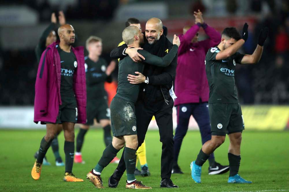Manchester City manager Pep Guardiola, centre right, and David Silva celebrate their victory after the final whistle of the game against Swansea City, during their English Premier League soccer match at the Liberty Stadium in Swansea, England, on Dec. 13. (Nick Potts / Associated Press files)
