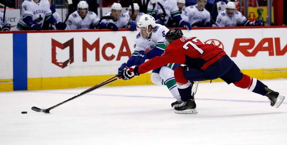 Vancouver Canucks right wing Brock Boeser and Washington Capitals right wing T.J. Oshie reach for the puck in the first period Jan. 9 in Washington. (Alex Brandon / Associated Press files)