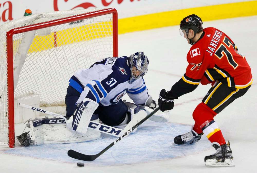 TODD KOROL / THE CANADIAN PRESS
Winnipeg Jets goalie Connor Hellebuyck (37) makes a save on Calgary Flames' Mark Jankowski during the shootout in their NHL hockey game in Calgary, Saturday, Jan. 20, 2018.
