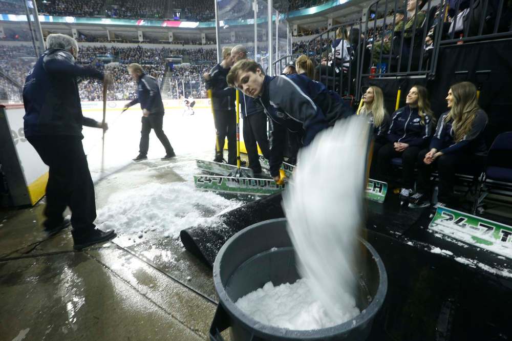 Jon Kapak shovels snow from the ice.