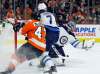 Connor Hellebuyck gloves a shot on goal as Philadelphia Flyers' Andrew MacDonald, left, and Ben Chiarot skate past during the second period. (Tom Mihalek / The Associated Press)