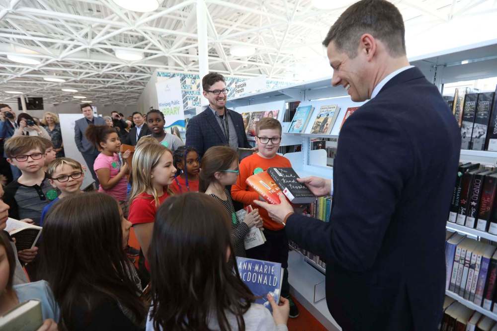 RUTH BONNEVILLE / WINNIPEG FREE PRES
Mayor Brian Bowman, right, and City Councillor Matt Allard hand out books to officially open the new Windsor Park Library Thursday.