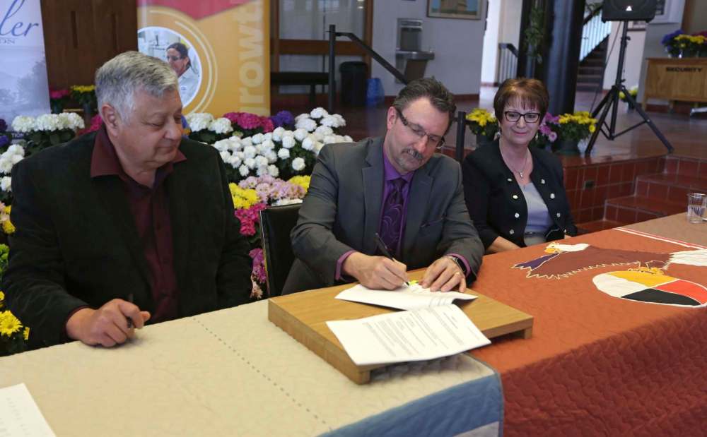 Jillian Austin / The Brandon Sun
Chief David LeDoux (left) and Brandon Mayor Rick Chrest sign the agreement Friday, with Indigenous Relations Minister Eileen Clarke.