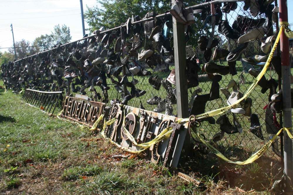 A fence on Heidelberg Street is covered in old, worn shoes.