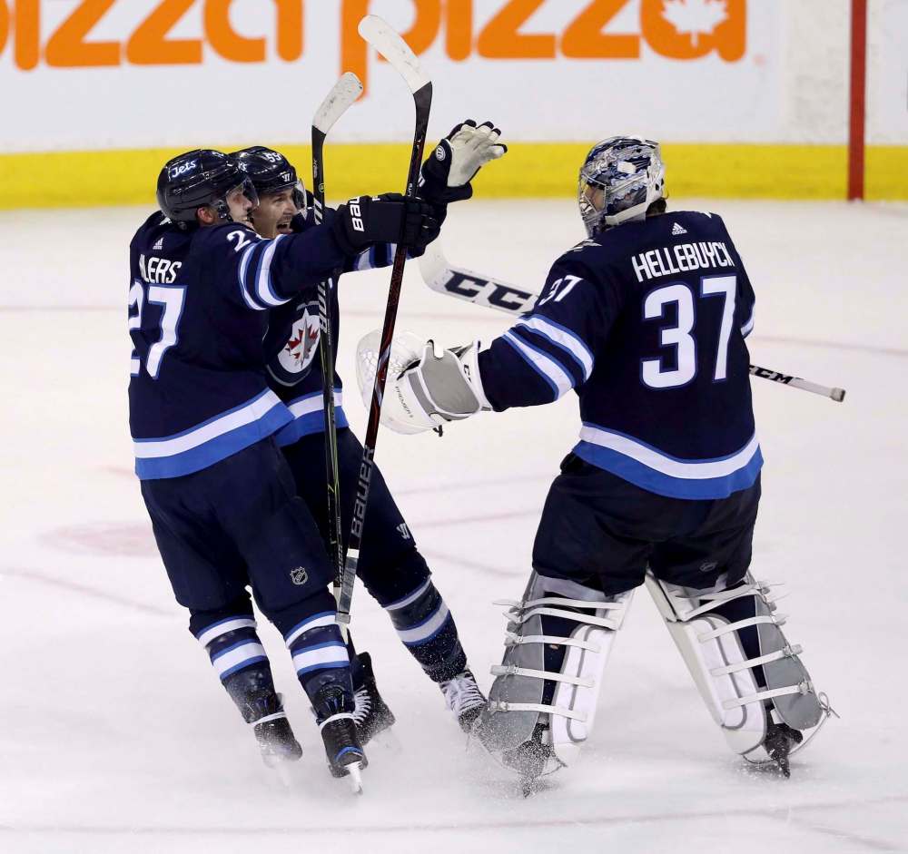 Trevor Hagan / The Canadian Press
Winnipeg Jets Nikolaj Ehlers (left) and Mark Scheifele rush to goaltender Connor Hellebuyck (37) after he made the game-winning save against the Nashville Predators Sunday.