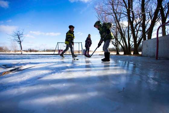 MIKAELA MACKENZIE / WINNIPEG FREE PRESSCaleb (left), Kyla, and Adam Nobel knock the puck around their backyard rink in Transcona.