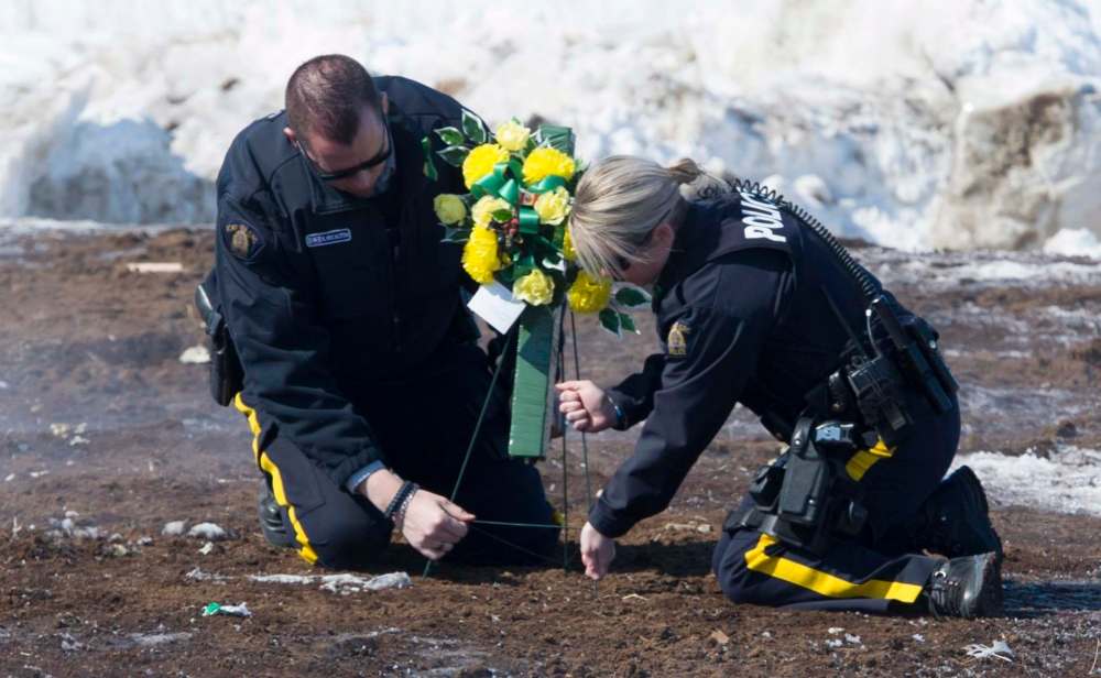 Jonathan Hayward
/ The Canadian Press
Members of the RCMP lay flowers at the intersection of a crash site near Tisdale, Sask., Sunday, April, 8, 2018. A bus carrying the Humboldt Broncos hockey team crashed into a truck en route to Nipawin for a game Friday night killing 15 and sending over a dozen more to the hospital.