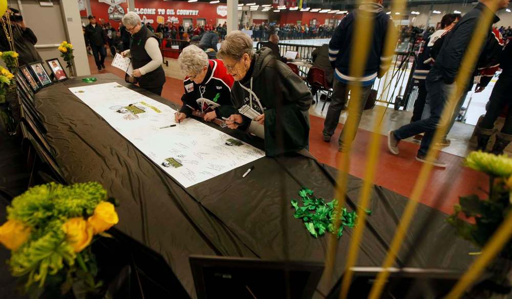 Virden Oil Capitals fans sign a tribute card to the Humbolt Broncos at the Virden Tundra Oil Gas Place Thursday. (Phil Hossack / Winnipeg Free Press)