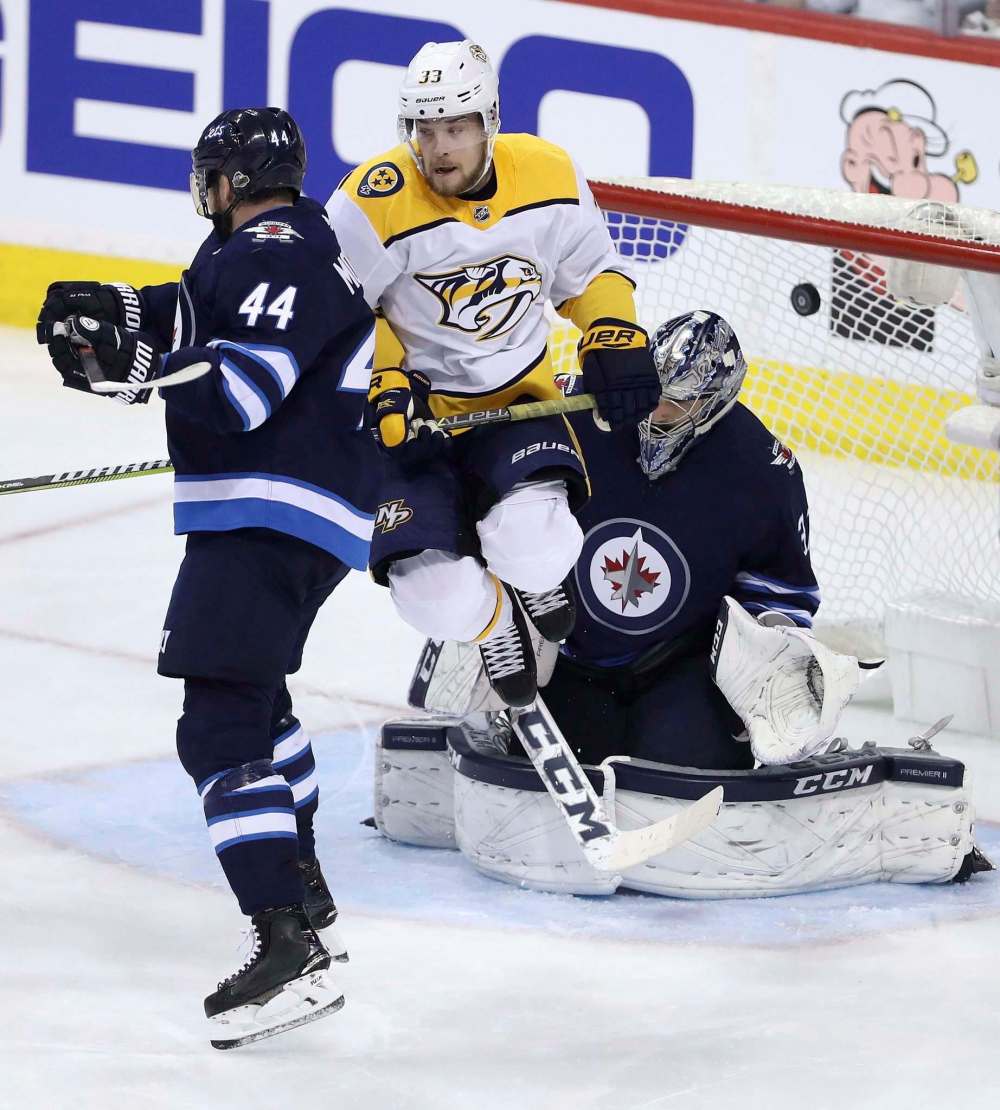 TREVOR HAGAN / THE CANADIAN PRESS FILES
The Nashville Predators’ Viktor Arvidsson takes a leap of faith to screen Winnipeg Jets goalie Connor Hellebuyck, vaulting into the air as pucks come whizzing in — and it’s been working.