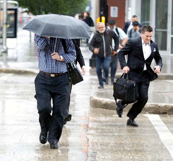 PHIL HOSSACK / WINNIPEG FREE PRESSA pedestrian seeks shelter under his umbrella while others sprint for cover during Wednesday afternoon's rush hour rain storm.