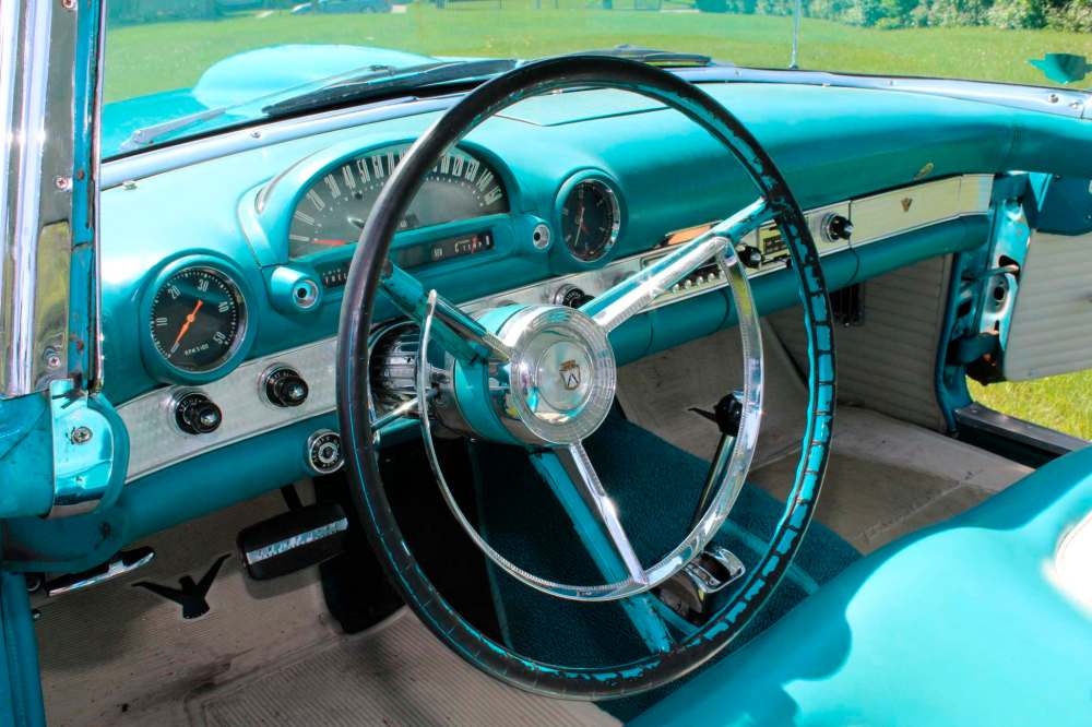 The ’56 T-bird’s interior is finished in blue and white vinyl and has an optional AM radio.