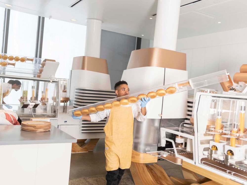 An employee refills the machine with rolls at the Creator storefront in San Francisco, California, U.S., on Monday, June 18, 2018. On June 27, the world's first robot-crafted burger will roll off a conveyor belt in San Francisco and into the hands of the public. The product, from Bay Area-based Creator, a culinary robotics company, is assembled and cooked in a machine that contains 20 computers, 350 sensors, and 50 actuator mechanisms. Photographer: Cayce Clifford/Bloomberg