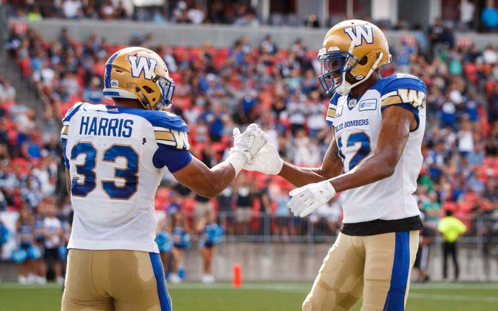 Winnipeg Blue Bombers' Andrew Harris celebrates his touchdown with teammate Adarius Bowman during the game against the Toronto Argonauts, in Toronto on Saturday. (Mark Blinch / The Canadian Press)