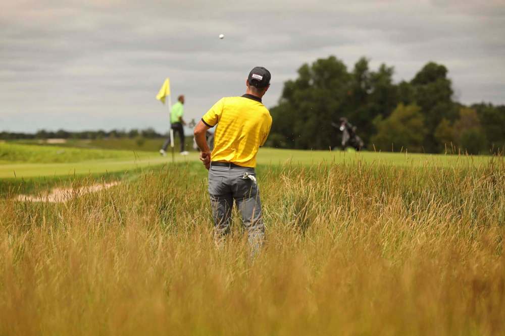 Connor Stewart hits his ball out of the fescue along the border of the 17th green while golfing with his friends at the Southwood Golf & Country Club Wednesday. (Ruth Bonneville / Winnipeg Free Press)
