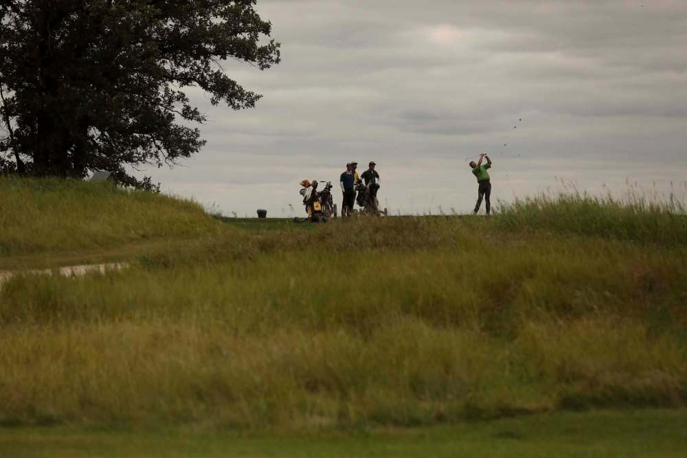 Tall grass surrounds a group of friends as they tee off on the 17th green while golfing at the Southwood Golf & Country Club Wednesday. (Ruth Bonneville / Winnipeg Free Press)