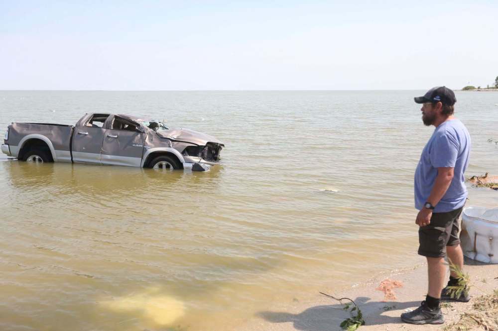 Shawn Gurke, a resident of Alonsa, watches a truck floating in Lake Manitoba after a tornado hit on Friday. (Melissa Verge / Brandon Sun)